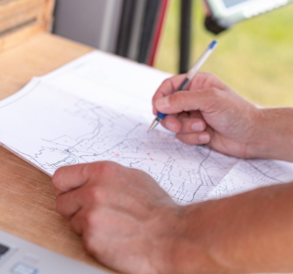 Eine Person notiert etwas auf einen Bauplan.