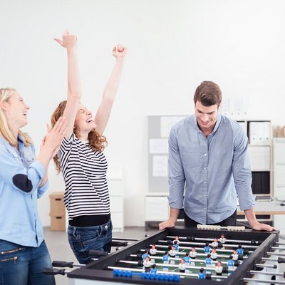 Eine Gruppe von Personen spielt Tischfußball im Büro Eine Gruppe von Personen spielt Tischfußball im Büro