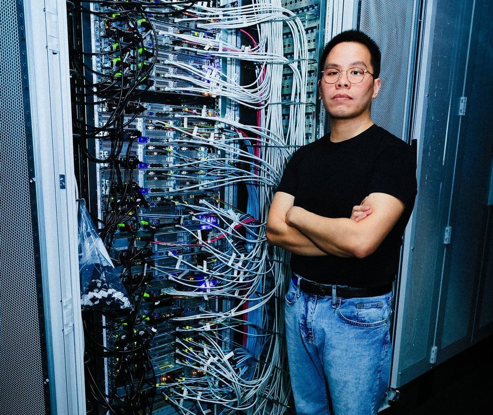 Ein ITler steht mit verschränkten Armen vor einem offenen Serverrack in einem Rechenzentrum.