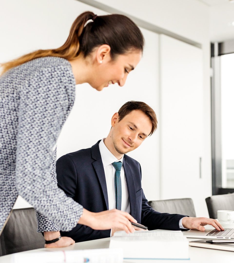 © Bayerisches Staatsministerium für Wohnen, Bau und Verkehr eine Frau zeigt einem Mann etwas auf einem Dokument.