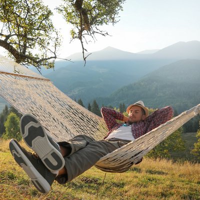 Ein Mann liegt entspannt in einer Hängematte. Ein Mann entspannt in einer Hängematte