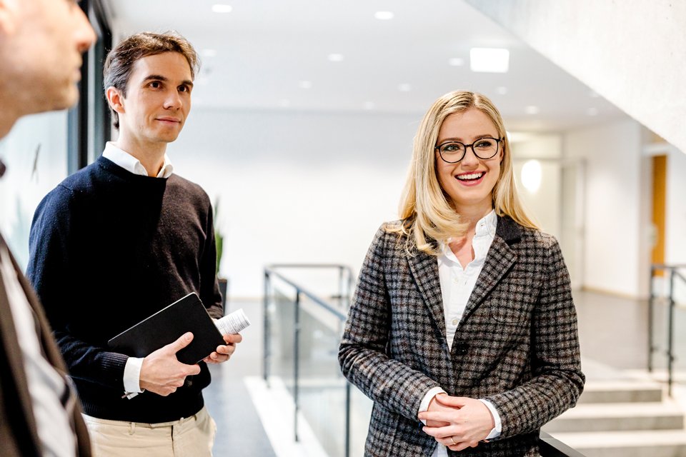© Bayerisches Staatsministerium für Wohnen, Bau und Verkehr Mehrere Personen stehen in den Fluren eines Bürogebäudes.
