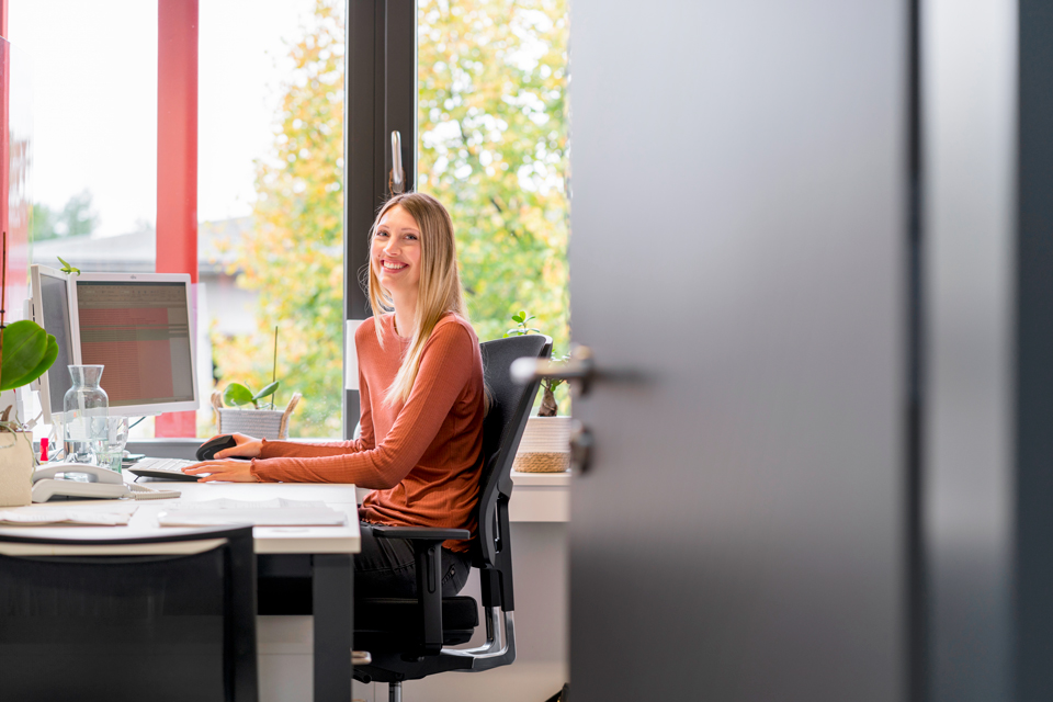 Eine lächelnde Frau sitzt am Schreibtisch